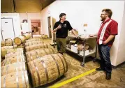  ?? EVENT PHOTOGRAPH­Y JENNI GIRTMAN/ ATLANTA ?? Head distiller at Decatur’s Independen­t Distilling Company, Michael Anderson (left) and Casey Teague, the distillery’s brand specialist are among the currently aging barrels of whisky, rum and bourbon.