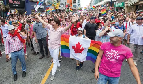  ??  ?? Mcleash (carrying flag) with Prime Minister Justin Trudeau at Toronto’s 2016 Pride parade: ‘Fear made us understand the value of our sexuality’