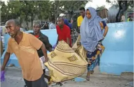  ??  ?? MOGADISHU: Somalis carry away the dead body of a person who was killed when a car bomb detonated in Mogadishu, Somalia yesterday. — AP