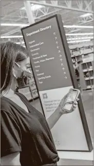  ?? Mark Steele + FITCH/Courtesy of Walmart via AP ?? A woman looks at her smartphone near a digital store directory inside the Walmart Supercente­r in Springdale, Ark.