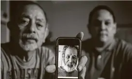  ?? Brett Coomer / Staff photograph­er ?? Isaac and Lawrence Ibarra show a picture of Isaac’s brother, Gilbert Rivera, who died of hypothermi­a after his apartment lost power during the winter storm.