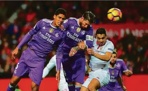  ?? AFP ?? Real Madrid’s defender Sergio Ramos (centre) heads into his own goal during the La Liga match against Sevilla at the Ramon Sanchez Pizjuan stadium on Sunday. Stevan Jovetic struck shortly after Ramos’ error to earn a 2-1 win for Sevilla.