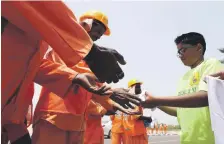  ??  ?? A young helper hands out water to workers in Dubai. Now all volunteers will have to be registered