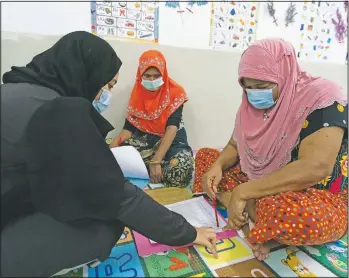  ??  ?? A volunteer teacher (left) gives a basic English lesson to refugees.