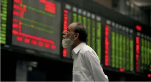  ?? — Reuters ?? A broker monitors an electronic board displaying stock prices during a trading session at the Karachi Stock Exchange.