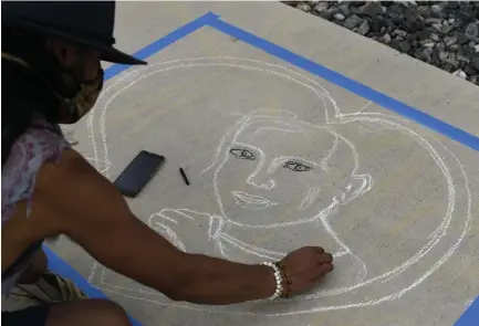  ?? Photos by Rachel Ellis, The Denver Post ?? Artist Cal Duran works on his chalk drawing honoring Rebecca Wingo, who was killed eight years ago by a gunman during a midnight screening of the latest Batman movie at an Aurora theater.