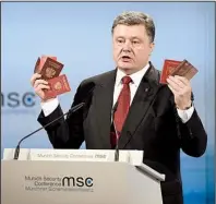  ?? AP/TOBIAS HASE ?? Ukrainian President Petro Poroshenko shows Russian passports that he said were proof of a Russian troop presence in eastern Ukraine during a speech Saturday at the Munich Security Conference.