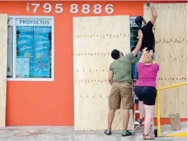  ??  ?? PREPARADOS. Los habitantes de Florida comenzaron a cubrir con madera puertas y ventanas para protegerse de Irma.