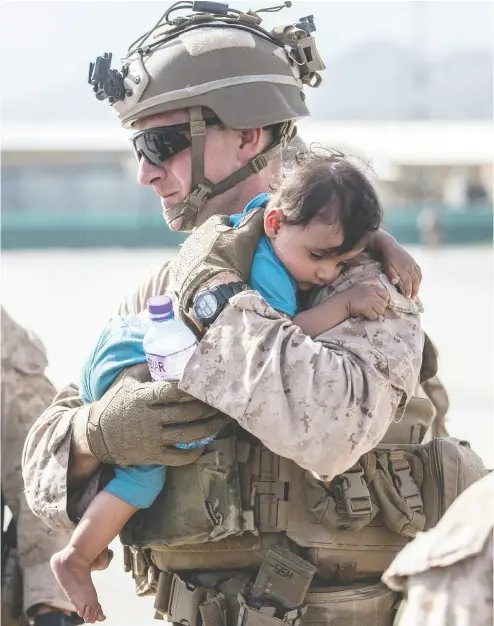  ?? U.S. MARINE CORPS / SGT. SAMUEL RUIZ / HANDOUT VIA REUTERS ?? A U.S. Marine calms an infant during an evacuation at Hamid Karzai Internatio­nal Airport in Kabul on Saturday.
Chaos and overcrowdi­ng continued to plague evacuation efforts.