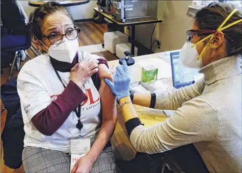  ?? Paul Buckowski / Times Union ?? Micky Jimenez, left, executive director of Capital District Latinos, receives her first dose of a COVID-19 vaccine Wednesday from Registered Nurse Cristina Baglio at a vaccinatio­n distributi­on site in
Albany.