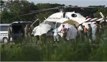  ??  ?? Police and military personnel use umbrellas to cover around a stretcher near a helicopter and an ambulance at a military airport in Chiang Rai as rescue operations continue for those still trapped inside the cave in Khun Nam Nang Non Forest Park in the...