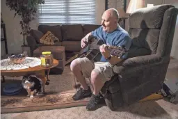  ??  ?? Jim Boerner, a U.S. Air Force veteran, almost lost his Mesa mobile home over a problem with his property tax payment. A guitar enthusiast, Boerner plays in his living room with his cat, Samantha, on July 8.