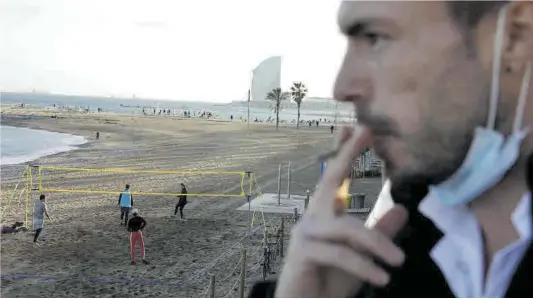  ?? Ferran Nadeu ?? Un hombre fuma un cigarrillo junto a la playa del Somorrostr­o de Barcelona, una de las cuatro de la prueba piloto, ayer por la tarde.
