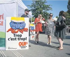  ?? REUTERS ?? Members of SVP next to a poster showing a cartoon worker wearing a belt studded with EU stars crushing the map of Switzerlan­d, in Geneva on Sept 13.