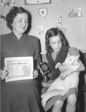  ?? THE COMMERCIAL APPEAL FILES ?? Feb. 17, 1951: Snowden, a cat adopted by Anne Louise Brown’s third-graders at Snowden School in the fall of 1950, was awarded a medal. The class received the Puss ’n’ Boots Bronze Award for elevating the cat “as man’s friend, loyal companion, vigilant protector.” Brown holds the citation while Ann Adams holds the medal and Snowden.