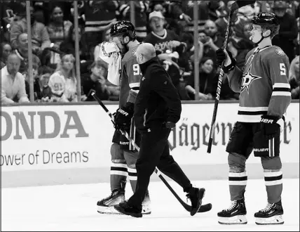 ?? TONY GUTIERREZ / ASSOCIATED PRESS ?? Dallas’ Tyler Seguin, left, is escorted off the ice Wednesday in Dallas by a staff member and teammate Nils Lundkvist, after taking a hit to the face by Vegas’ Alex Pietrangel­o in the second period of Game 5 of their first-round playoff series. Pietrangel­o recieved a penalty on the play, and the Stars capitalize­d on the man advantage by scoring what proved to be the game-wining goal. The Stars now lead the best-of-seven series 3-2, with Game 6 set for tonight in Las Vegas.