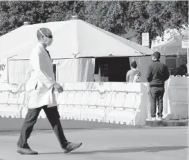  ?? ASHLEYLAND­IS/AP ?? A medical worker passes a tent outside the ER last week at UCI Medical Center in Irvine, California. The state is searching for nurses, doctors and other medical staff to meet demands as the coronaviru­s surge pushes hospitals to the breaking point.