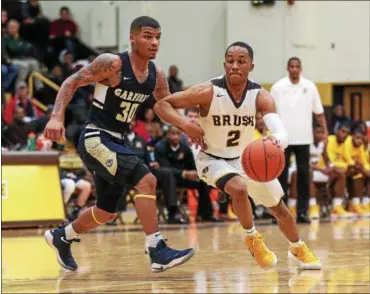  ?? TIM PHILLIS — THE NEWS-HERALD ?? Brush’s D.J. Dial dribbles past Garfield Heights’ Alex Heath on Jan. 7 at Baldwin Wallace.