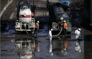  ??  ?? A work crew cleans up an area of Highway 101 that flooded in Montecito on Friday. The number of missing after a California mudslide has fluctuated wildly, due to shifting definition­s, the inherent uncertaint­y that follows a natural disaster, and just...