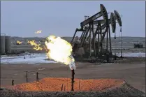  ?? ERIC GAY / AP 2014 ?? Oil pump jacks work behind a natural gas flare near Watford City, N.D. The price of oil is down 34 percent from its high of $61.43 this year, and 62 percent from its high of $107.26 last year.