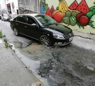  ?? Robson Ventura/Folhapress ?? Motorista tenta desviar de buraco na rua Julio Rodrigues Mendes, no Tucuruvi (zona norte), onde há vazamento de esgoto; moradores reclamam de mau cheiro