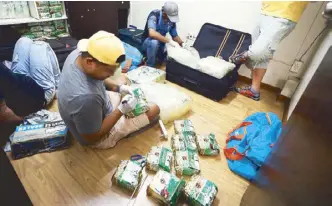  ?? MIGUEL DE GUZMAN ?? Anti-narcotics agents inspect shabu stuffed in Chinese green tea during a raid in Barangay San Antonio, Makati on Tuesday night.