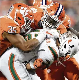  ?? MIKE COMER / GETTY IMAGES ?? Justin Foster (left, part of a gang tackling Miami’s Malik Rosier last season) is back for a Clemson defensive front that could supply three top-10 picks in next spring’s draft. That’s among the reasons Kirk Bohls has the Tigers No. 1.