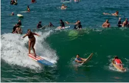  ?? — AFP ?? Surfers fight for a wave after large swells caused by Hurricane Marie continued to pound the California­n coast at Venice Beach on Saturday.