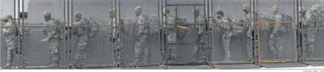  ?? JUSTIN LANE / EFE ?? Tropas de la Guardia Nacional pasan ayer por la valla que rodea el edificio del Capitolio en Washington.