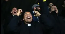  ?? CHRISTOPHE­R FURLONG/GETTY IMAGES ?? Vatican seminarian­s and priests enjoy the action during the Clericus Cup. The tournament, modelled after the World Cup, is played on a hilltop within Vatican City with a view of St. Peter’s Basilica in the background.