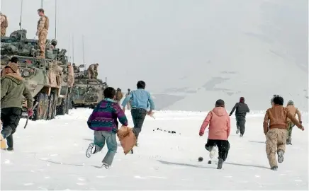  ?? US ARMY ?? Afghan children run to a firing range to collect the expended brass after members of New Zealand Army teams conducted a live-fire exercise in Bamyan Province, Afghanista­n, in 2013.