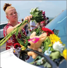  ?? AP/CHARLIE RIEDEL ?? Jasmine Burkhardt leaves flowers Friday on a vehicle believed to belong to a victim of Thursday night’s duck boat accident in Branson, Mo.