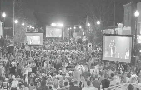  ??  ?? On the main street of Bobcaygeon, Ont., fans watch The Tragically Hip’s final concert on video screens.