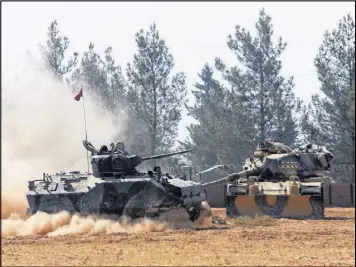  ?? IHA ?? A Turkish army tank and another armored vehicle are stationed near the border with Syria, in Karkamis, Turkey, on Tuesday. Turkish media reports say Turkish artillery launched new strikes at Islamic State targets across the border.
