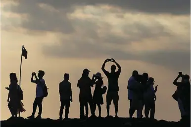  ?? JOHANNES P. CHRISTO/REUTERS ?? TUJUAN FAVORIT: Sejumlah turis menikmati sunset di Tanah Lot, Tabanan, Bali.