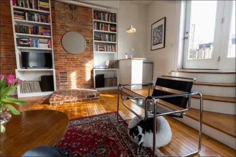  ?? TYGER WILLIAMS — THE PHILADELPH­IA INQUIRER ?? Kate Levy’s living space on the second floor of her apartment features exposed brick walls, tiered steps to the balcony, plants, a protector screen, and secondhand furniture.