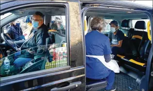  ?? ALASTAIR GRANT/AP ?? Dr. Tamara Joffe prepares to administer a COVID-19 jab using the Astrazenec­a vaccine to Leslie Reid in the back of a London taxi cab during the pilot project of Vaxi Taxi, which aims to help ferry supplies and patients to temporary clinics set up in faith and community centers across the city.