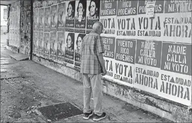  ??  ?? A man reads campaign posters in San Juan before the vote on Puerto Rican statehood. (Photograph: Ricardo Arduengo/AFP/ Getty Images)