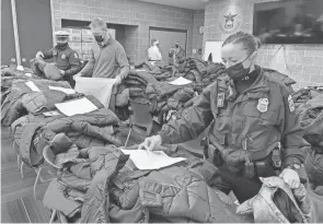  ?? ANGELA REIGHARD / COLUMBUS DEPARTMENT OF PUBLIC SAFETY ?? Columbus police officers and volunteers from the Starfish Assignment sort through hundreds of children’s coats at the Columbus Police 1 Precinct Substation in Westervill­e on Friday. This was the fourth annual coat drive hosted by the division.