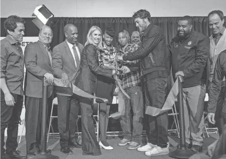  ?? MANDI WRIGHT/DETROIT FREE PRESS ?? Mitch Albom, far left, watches as Detroit Mayor Mike Duggan and City Council member Scott Benson help Kelly and Matthew Stafford cut a ribbon for the new Kelly and Matthew Stafford and Friends Education Center in Detroit on Monday.