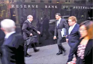  ?? JASON REED/REUTERS/THE STRAITS TIMES ?? Business people walk outside the Reserve Bank of Australia in Sydney on May 5, 2015.