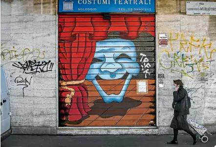  ?? AP ?? A woman wearing a mask walks past a closed shop in Milan after all of Italy went into lockdown because of the spread of coronaviru­s.
