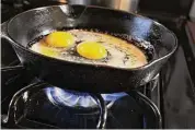  ?? Scott Olson / Getty Images ?? Eggs cook in a cast iron pan over flames on a natural gas burning stove on Jan. 12 in Chicago. Connecticu­t legislatio­n is seeking to create air quality standards for gas stoves in the state.