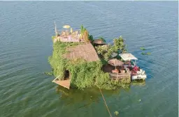  ?? PATRICK ONEN/AP ?? A floating restaurant and bar is seen from the air Feb. 18 in Lake Victoria near the Luzira area of Kampala, Uganda. Flowering plants rise from the water into the hull.