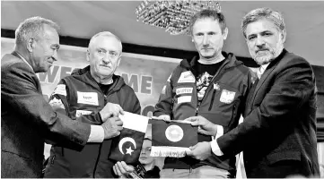  ??  ?? Wielicki (second left), who will run a Polish expedition to scale K2 in winter, holds the Pakistani national flag as he poses for a picture with officials after a news conference in Islamabad. — Reuters photo