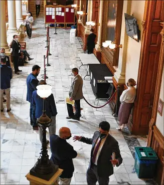  ?? HYOSUB SHIN/ HYOSUB.SHIN@AJC.COM ?? Lobbyists mill around outside the state Capitol Room 341 watching a committee meeting on a TV screen Tuesday, the day before the final chance for a bill to become law.