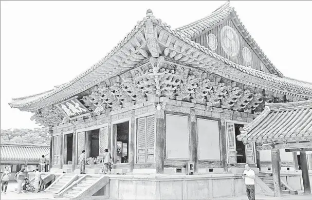  ??  ?? Visitors gaze into a pavilion at the 8th-century Bulguksa Temple, once the capital of the Silla Dynasty, in the Gyeong-ju area of Busan, South Korea. A 30-minute hike leads to the Seokguram Grotto, a carved-granite cave temple. — Photos for The...