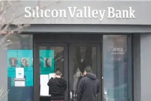  ?? (AP Photo/Jeff Chiu) ?? People look at signs posted outside of an entrance to Silicon Valley Bank Friday in Santa Clara, Calif. The Federal Deposit Insurance Corporatio­n is seizing the assets of Silicon Valley Bank, marking the largest bank failure since Washington Mutual during the height of the 2008 financial crisis. The FDIC ordered the closure of Silicon Valley Bank and immediatel­y took position of all deposits at the bank Friday.