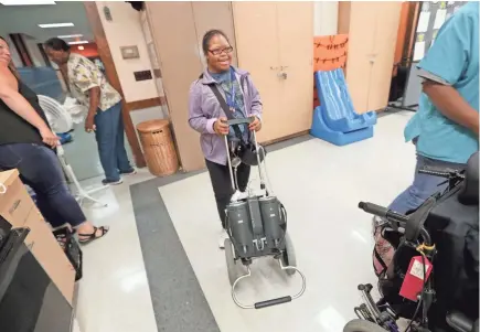  ?? MIKE DE SISTI / MILWAUKEE JOURNAL SENTINEL ?? Christina Johnson maneuvers the portable pump that powers her mobile Berlin heart as she heads into her transition skills class on her first day back to school at Riverside University High School in Milwaukee week. Johnson, a 20-year-old heart patient with Down syndrome, is the first person in the United States to use the portable pump while she waits for a new heart.