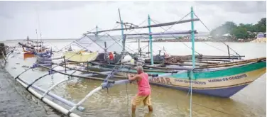  ?? Agence France-presse ?? ↑
A fisherman secures his boat along the seashore of Borongan in Samar in preparatio­n of Typhoon Surigae on Sunday.